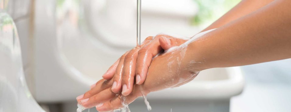 Closeup woman washing hands with soap under the faucet with water in the bathroom.